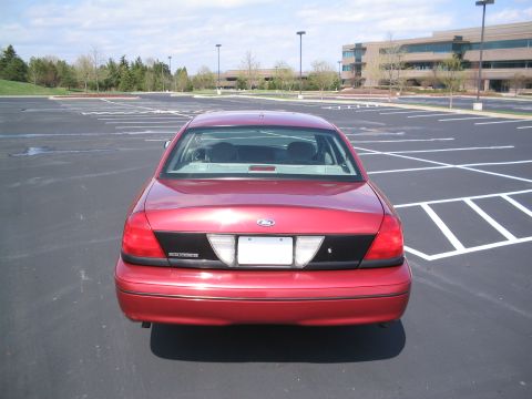 2001 Ford Crown Victoria - Rear view of a red 2001 Ford Crown Victoria sedan in a large, mostly empty parking lot.