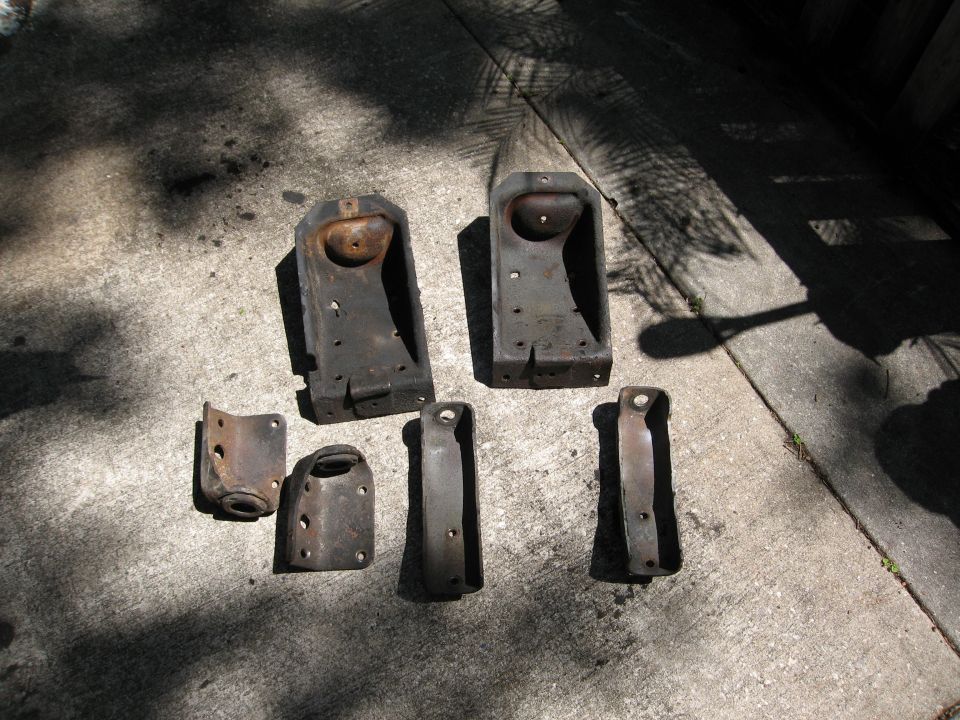 Several metal brackets and suspension components laid out on concrete