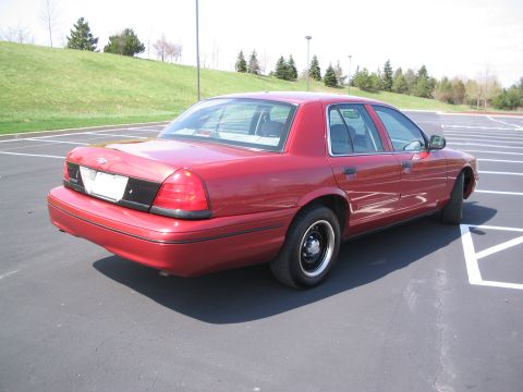2001 Ford Crown Victoria - Rear 3/4 view of a red 2001 Ford Crown Victoria parked in a lot.