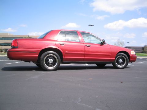 2001 Ford Crown Victoria - A red 2001 Ford Crown Victoria is shown from the side in a parking lot with a building in the background.