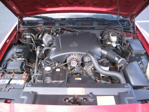 2001 Ford Crown Victoria - The engine bay of a red 2001 Ford Crown Victoria is shown with the hood raised, revealing the V8 engine and associated components.