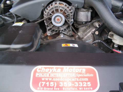 2001 Ford Crown Victoria - Close-up of an engine bay, an alternator, fan, and a sticker for Cheyka Motors, Police Interceptor Specialists.