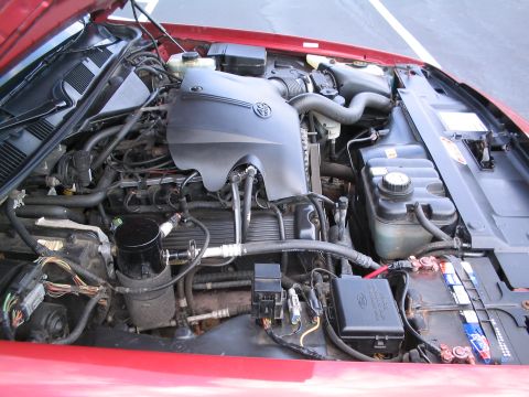 2001 Ford Crown Victoria - The engine compartment of a red vehicle is visible, with the hood open, revealing the engine and associated components.