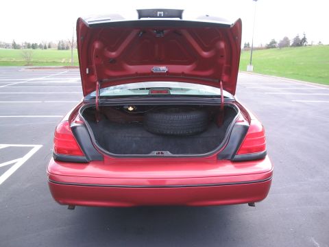 2001 Ford Crown Victoria - The rear of a red 2001 Ford Crown Victoria is shown with the trunk open, revealing a spare tire.