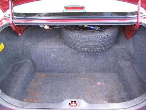 2001 Ford Crown Victoria - Car trunk interior with spare tire and jack visible. The carpet shows some wear and staining.