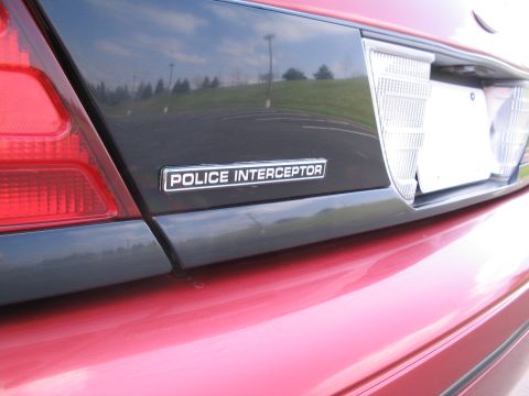 2001 Ford Crown Victoria - Close-up of the rear of a red vehicle, a "POLICE INTERCEPTOR" badge and part of a taillight.