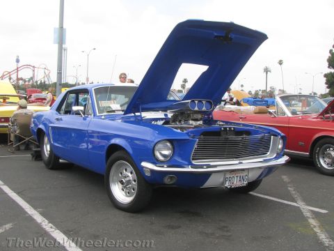 1968 Ford Mustang - A blue 1969 Ford Mustang with a prominent supercharger is displayed at an outdoor car show.