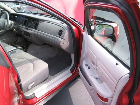 2001 Ford Crown Victoria - The interior of a 2001 Ford Crown Victoria shows light gray seats and a gray dashboard with the driver's door open.