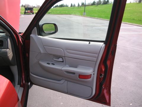 2001 Ford Crown Victoria - Interior view of a red 2001 Ford Crown Victoria showing the driver's side door panel and controls.