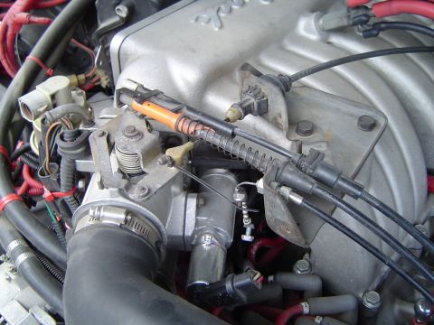 1989 Ford Bronco - Close-up view of engine components, focusing on the throttle body and associated cables.