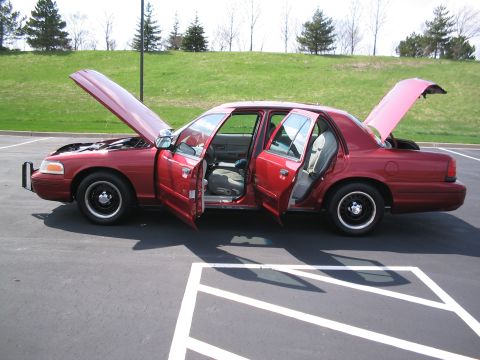 2001 Ford Crown Victoria - Red 2001 Ford Crown Victoria with all doors, hood, and trunk open, parked in a lot.