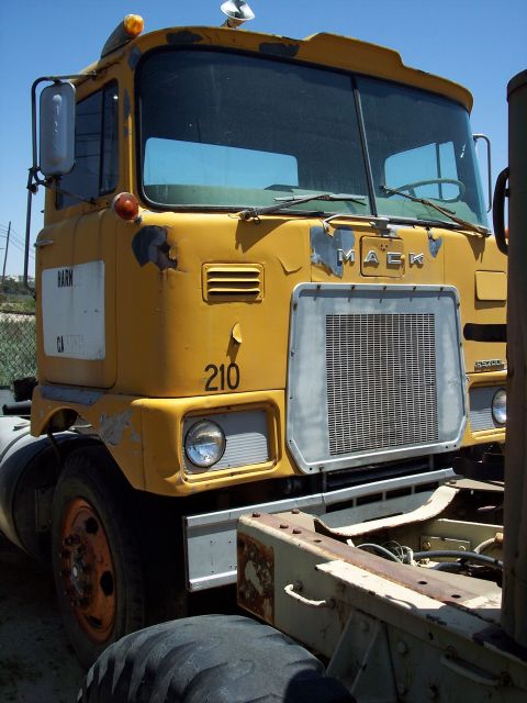 1981 Kenworth W900A - A yellow MACK truck is seen from the front, displaying the 'MACK' emblem on its grille and the number '210' on the fender.