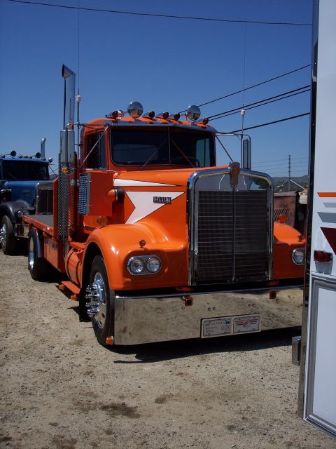 1981 Kenworth W900A - An orange Kenworth semi-truck is parked outdoors, with another truck visible behind it.
