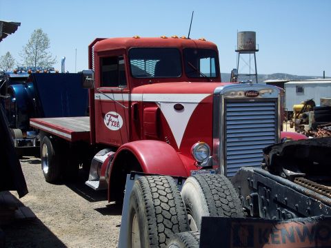 1981 Kenworth W900A - A red flatbed truck with a distinctive white stripe and logo is parked outdoors.