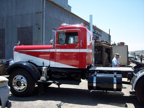 1981 Kenworth W900A - A classic semi-truck with a red and white paint scheme is parked outdoors, with a man standing in the background.