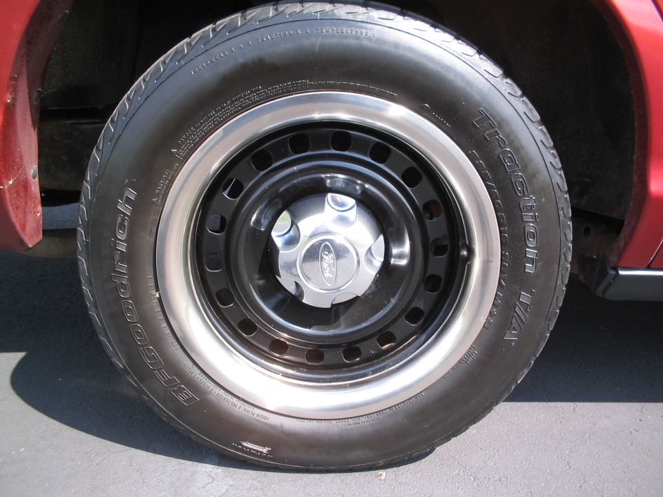 Red car wheel with BFGoodrich Traction T/A tire and Ford hubcap on black steel rim