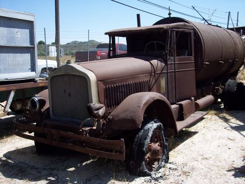 1981 Kenworth W900A - An old, heavily rusted tanker truck sits in an outdoor lot with a damaged front tire.