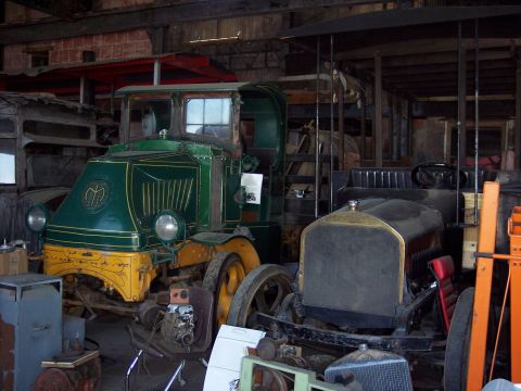 1981 Kenworth W900A - Two vintage trucks are stored indoors, one with a green and yellow cab and the other a black open-top vehicle.