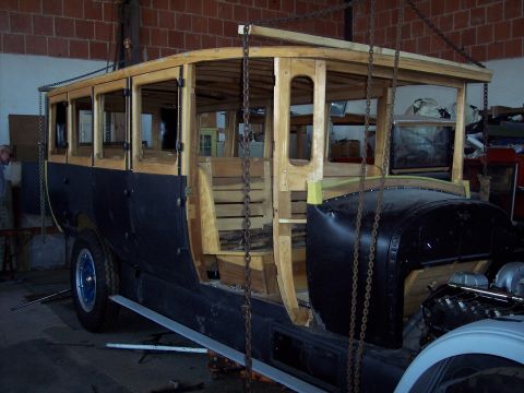 1981 Kenworth W900A - A bus body, partially constructed with wood, is suspended for work in a garage setting.