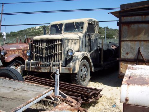 1981 Kenworth W900A - An old truck sits in a yard next to another rusty vehicle under a clear blue sky.