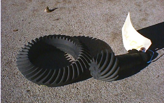 Ring and pinion gear set laid on concrete with a rag and bottle nearby