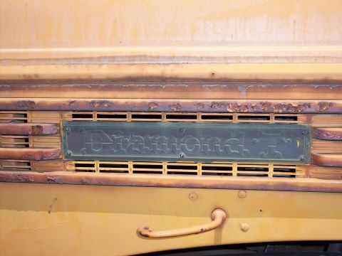 1981 Kenworth W900A - Close-up of a Diamond T badge on a weathered yellow truck grille.