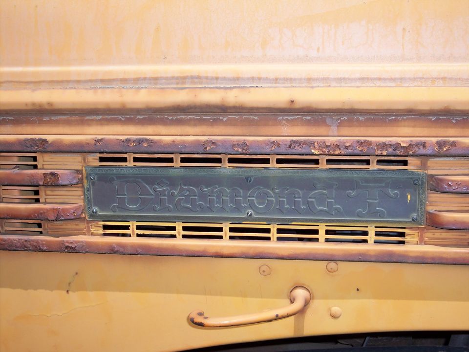 Diamond T badge on a yellow truck grille with rust