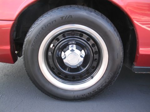 2001 Ford Crown Victoria - Close-up of a red car's wheel a black rim, chrome hubcap, and BFGoodrich Traction T/A tire.