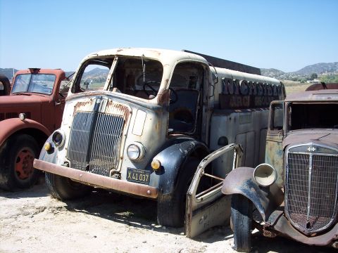 1981 Kenworth W900A - This vintage Richfield gasoline truck is in a state of disrepair, surrounded by other weathered vehicles under a clear sky.