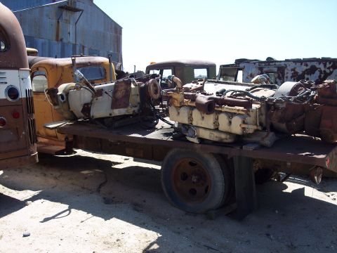 1981 Kenworth W900A - Two V-engines are transported on a flatbed trailer at a junkyard.