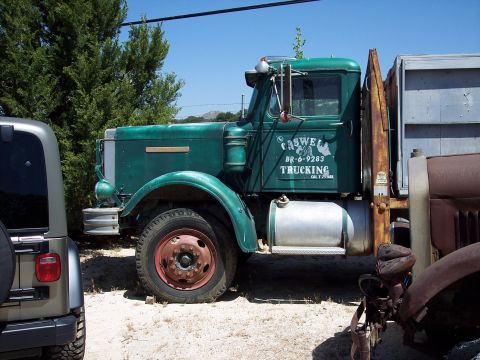 1981 Kenworth W900A - A vintage green truck with "CASWELL TRUCKING" text is parked next to another vehicle.