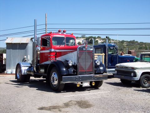 1981 Kenworth W900A - A classic red and silver semi-truck is parked next to other vehicles under a clear blue sky.