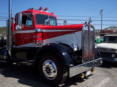 1981 Kenworth W900A - A classic red and white Kenworth truck is seen parked outdoors with another vehicle in the background.