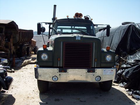 1981 Kenworth W900A - This International truck is parked outdoors with other vehicles and covered items around it.