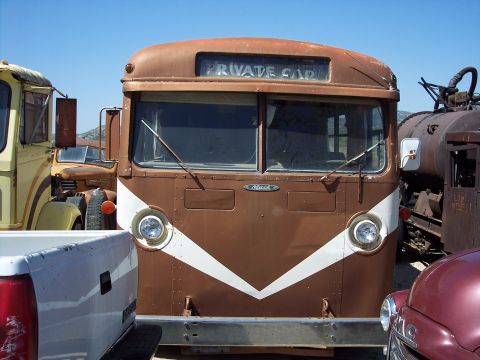 1981 Kenworth W900A - Front view of a vintage Mack bus with "PRIVATE CAR" displayed, surrounded by other vehicles in a lot.