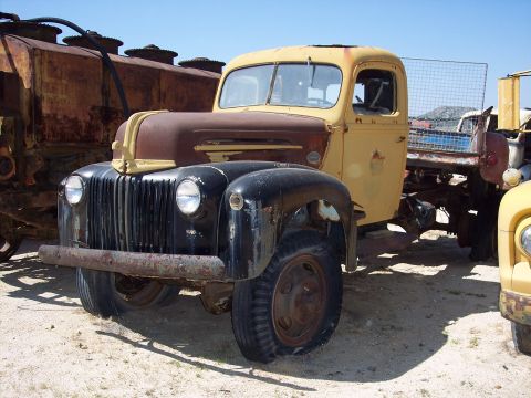 1981 Kenworth W900A - A weathered yellow and brown truck sits in a yard with other vehicles.