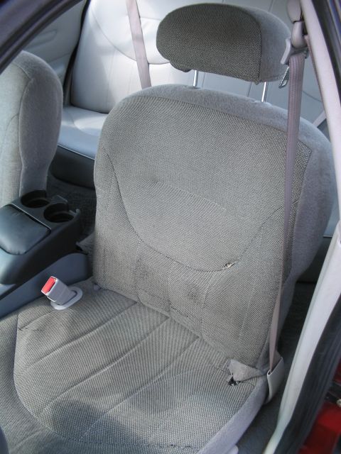 2001 Ford Crown Victoria - Interior view of a car showing worn fabric seats and a center console with cup holders.