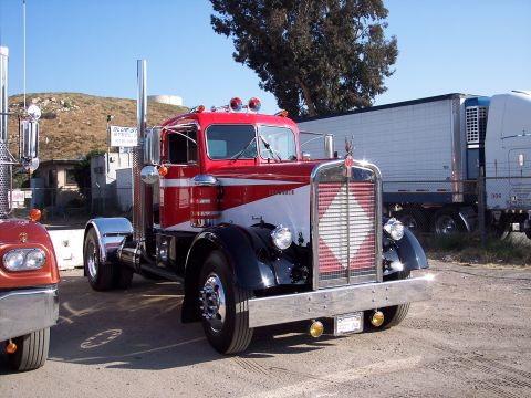 1981 Kenworth W900A - A classic red and white Kenworth semi-truck is parked outdoors next to a trailer.