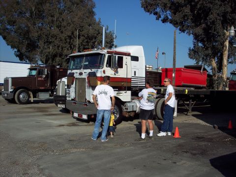 1981 Kenworth W900A - A group of men stand near a 1981 Kenworth W900A truck at an outdoor gathering.