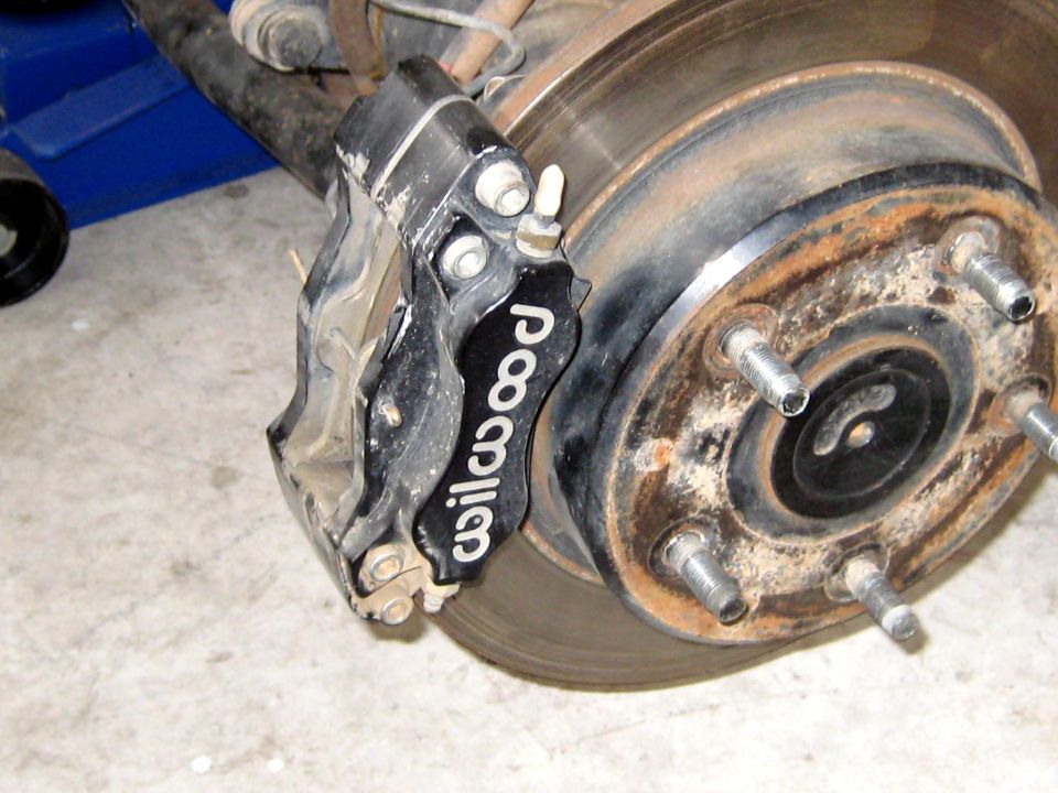 Black Wilwood brake caliper on a rusty rotor
