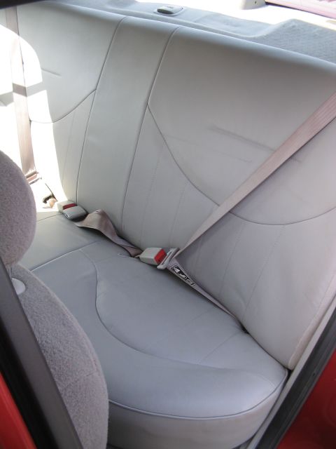 2001 Ford Crown Victoria - The interior of a car shows light gray leather rear seats with beige seatbelts and red buckles.