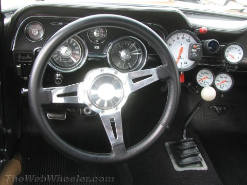 1968 Ford Mustang - The interior of a 1968 Ford Mustang shows a custom steering wheel and multiple gauges.