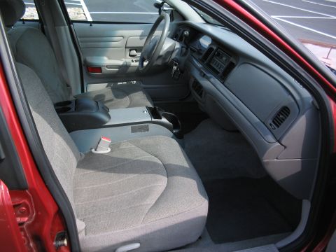 2001 Ford Crown Victoria - Interior view of a red 2001 Ford Crown Victoria, showing the front seats, dashboard, and center console.