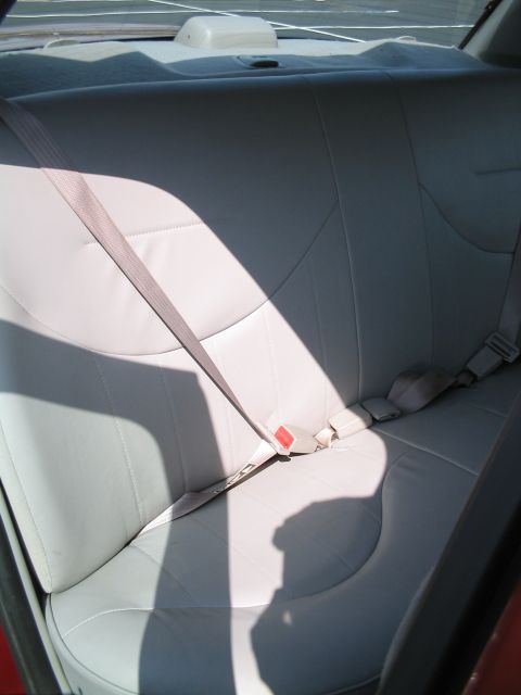 2001 Ford Crown Victoria - The interior of a vehicle shows the rear seat and seatbelts, with sunlight casting shadows.