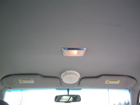 2001 Ford Crown Victoria - The interior ceiling of a vehicle, a central dome light and two illuminated sun visors.
