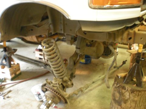 1993 Ford Bronco - Front suspension of a 1993 Ford Bronco undergoing work, with coil springs visible on jack stands.