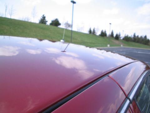 2001 Ford Crown Victoria - The reflection of clouds on the car's roof is visible, with a grassy hill and streetlights in the background.