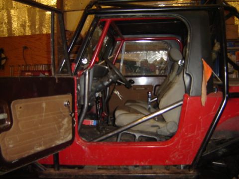 1992 Ford Bronco - This modified Jeep features a prominent roll cage and an open driver's side door revealing the interior.