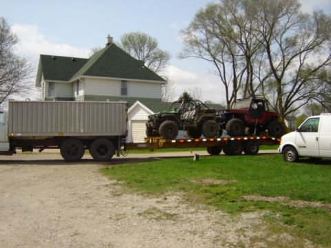 1992 Ford Bronco - Two off-road vehicles are transported on a trailer, accompanied by a truck and a van.