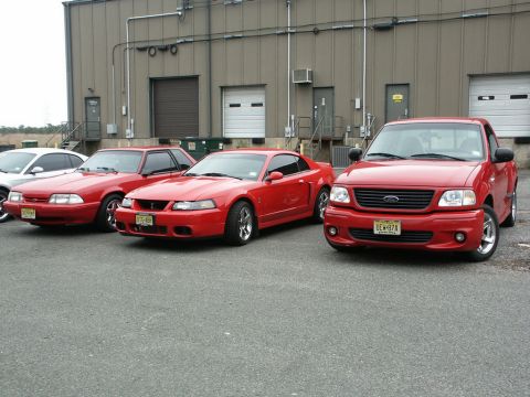 2001 Mercury Grand Marquis - A red Ford F-150 Lightning pickup truck is parked in front of a building with other vehicles.